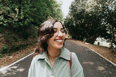 woman in a blue shirt and glasses smiles wide