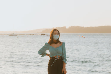 woman in a facemask stands in front of large lake