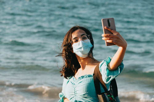 woman in a facemask takes a selfie with her phone