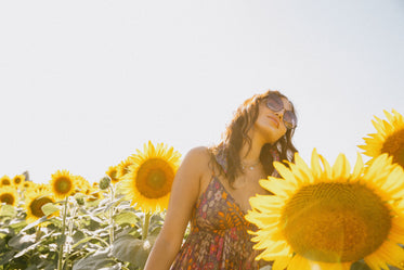 woman in a floral dress surrounded by sunflowers