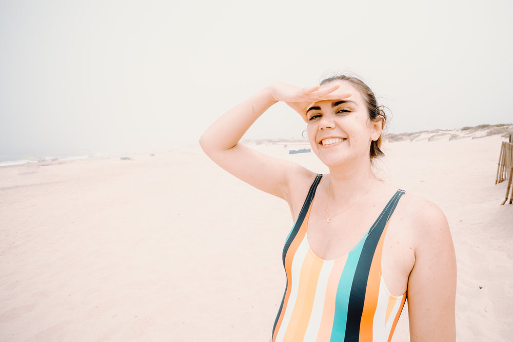 woman in a swimsuit shields her eyes from the sun