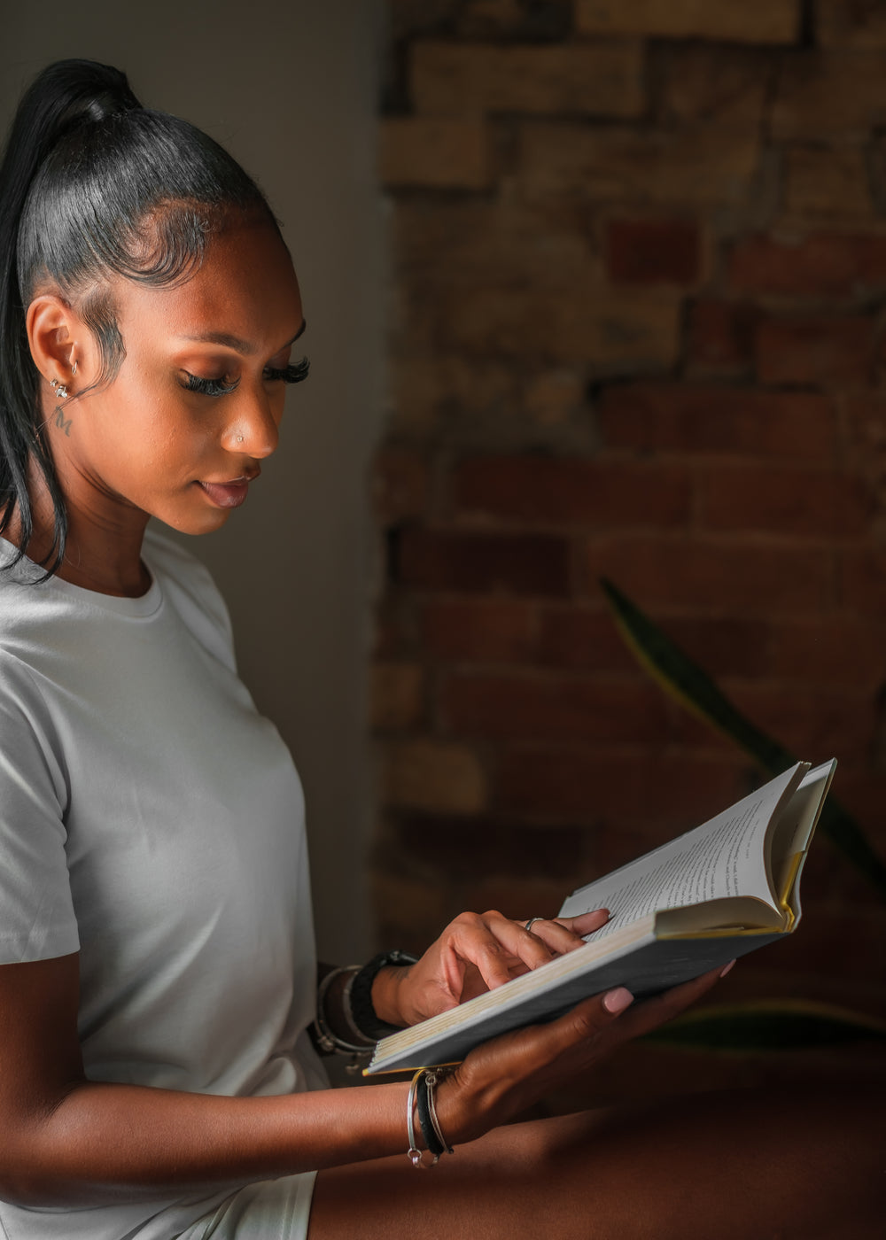 woman in a white shirt holds a novel in her hands