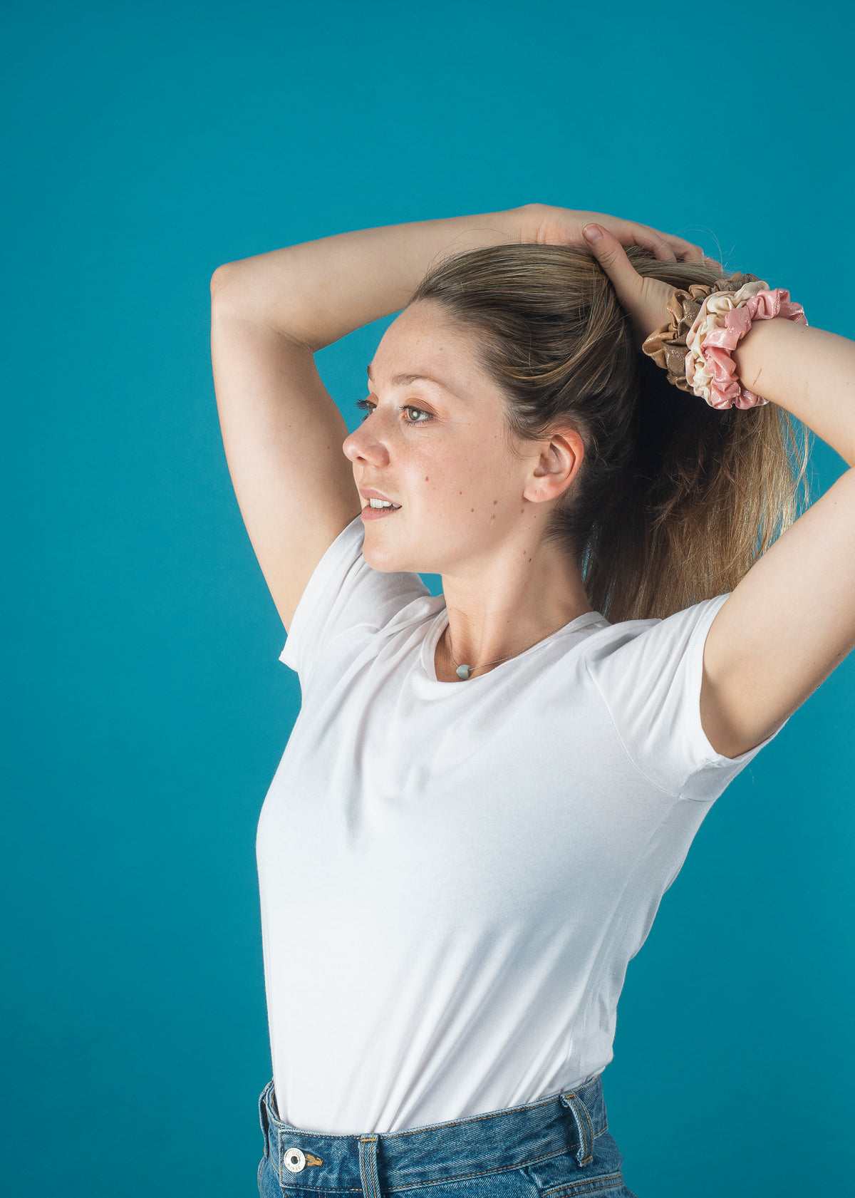 woman in a white shirt puts her hair up with scrunchies