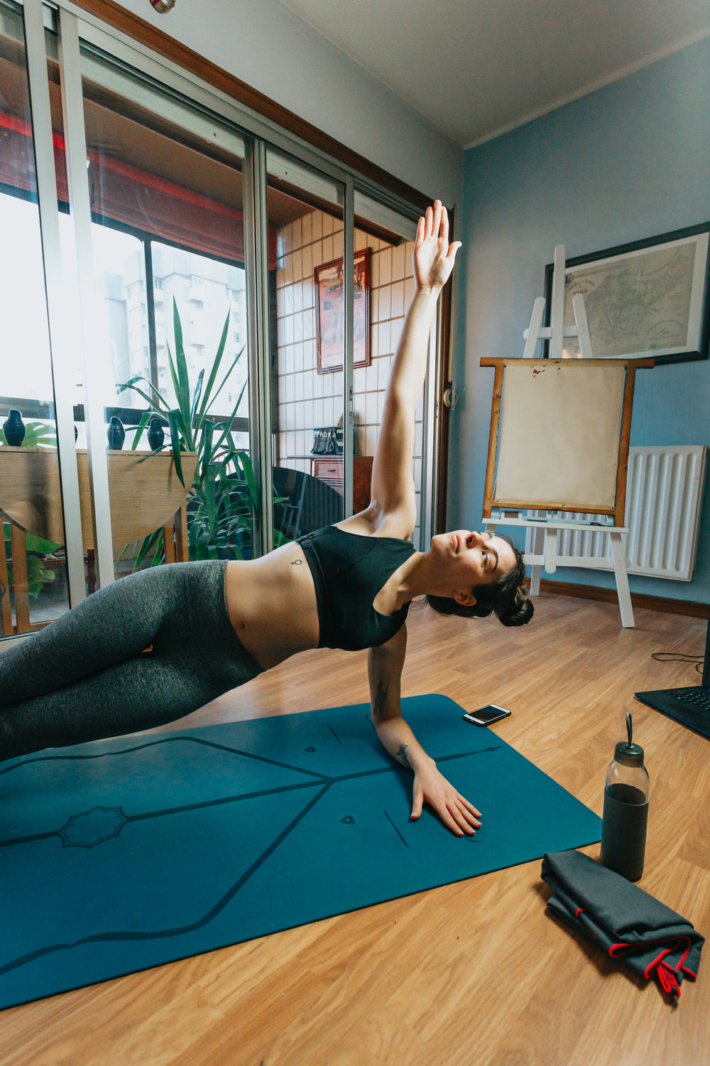 woman in a yoga pose in her living room on a blue yoga mat