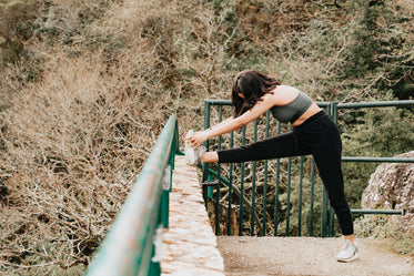 woman in active wear stretches her leg outdoors