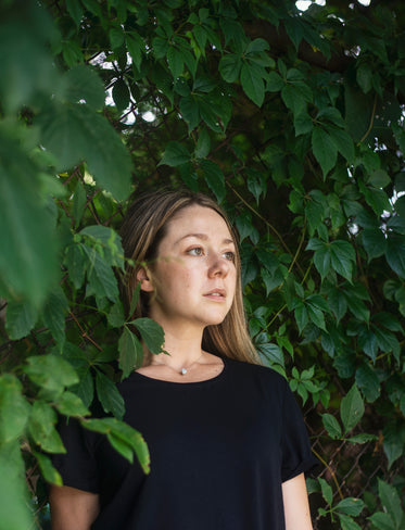 woman in black surrounded by green vines