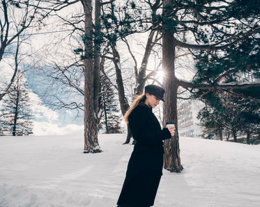 woman in black trench in winter woods