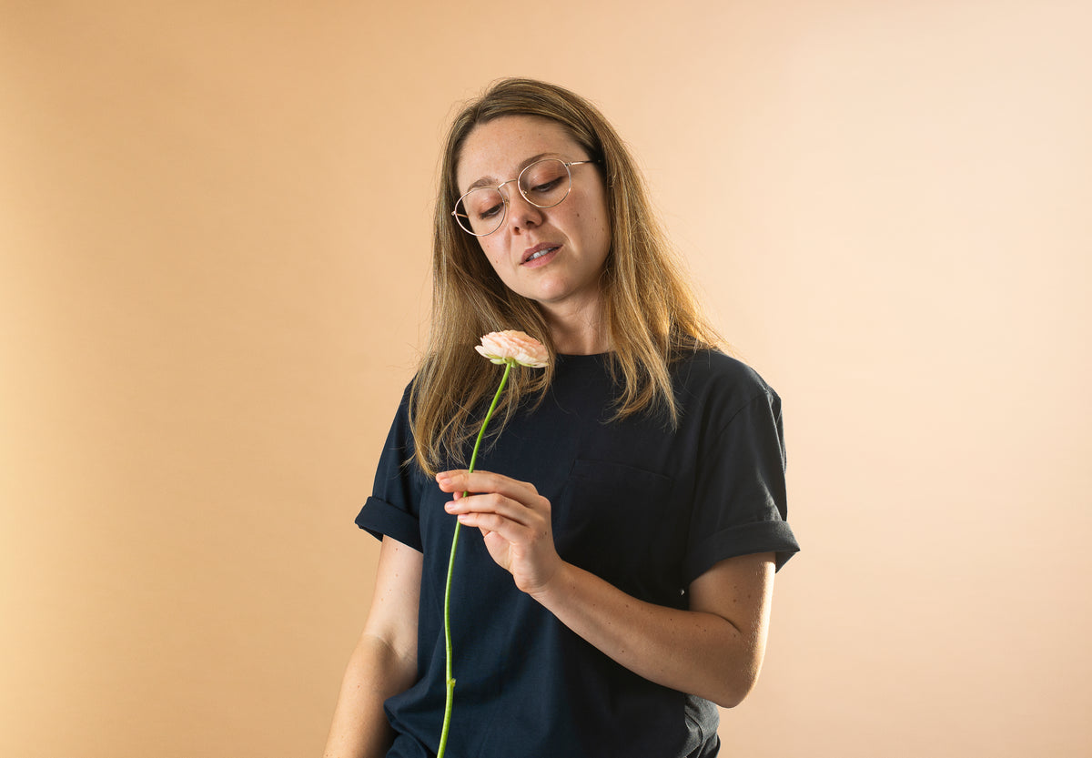 woman in blue shirt holding a single long stem flower
