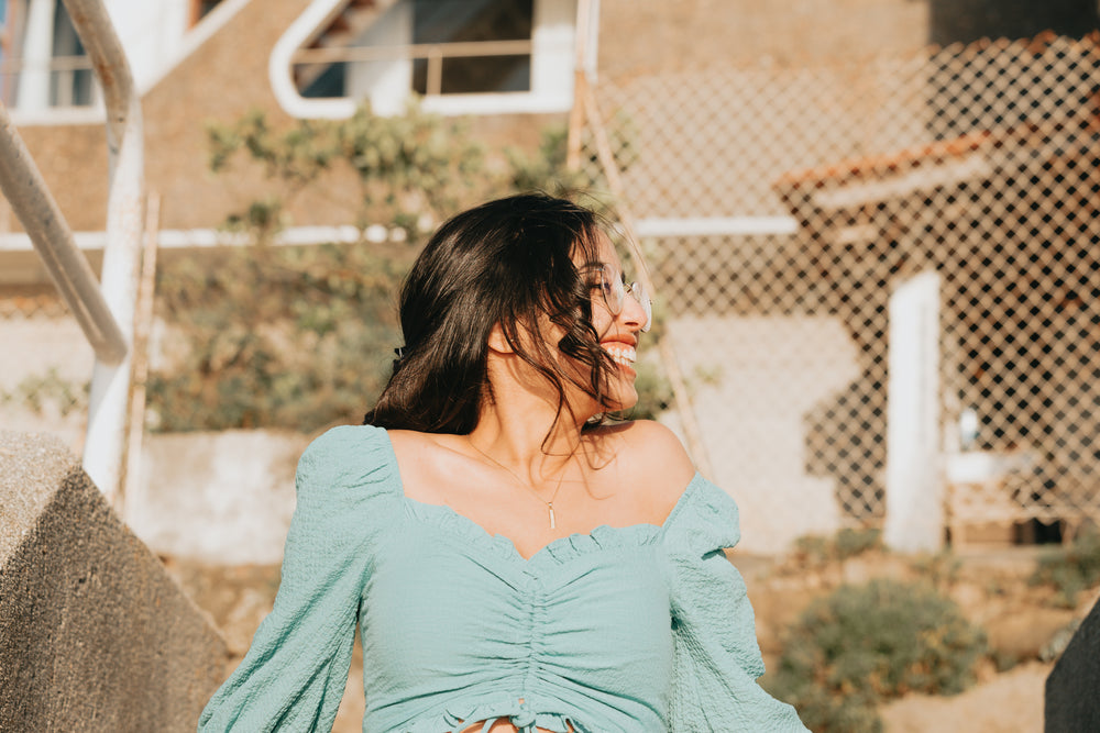 woman in blue smiles and leans back outdoors