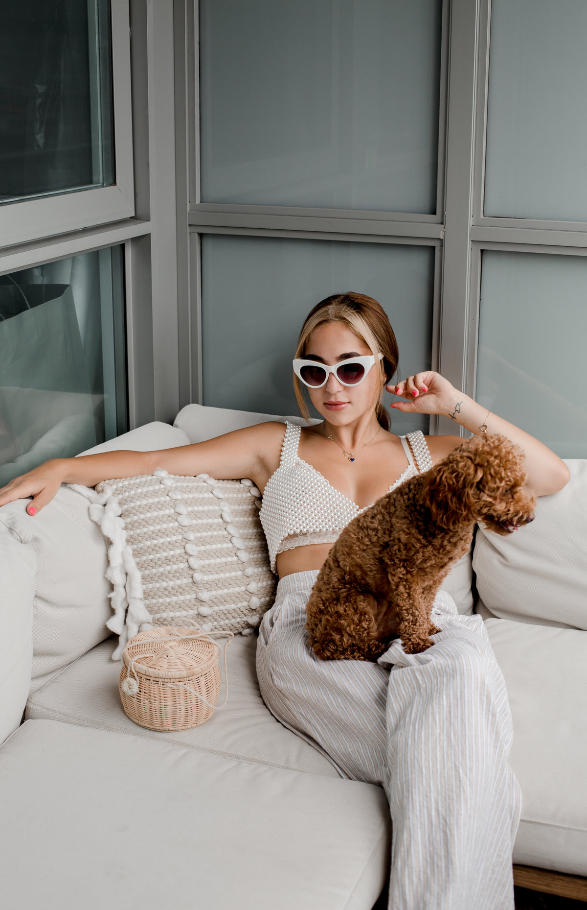 woman in cateye sunglasses sits with a puppy