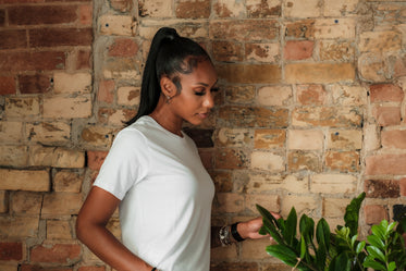 woman in crisp white shirt looking at house plants