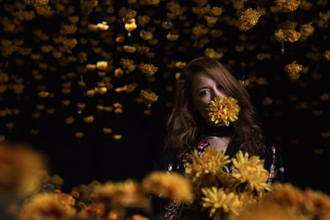 woman in darkness holds a yellow flower in her mouth