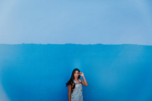 woman in front of blue wall adjusts glasses