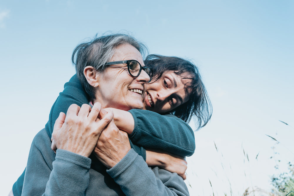 woman in glasses gets hugged from behind by a friend