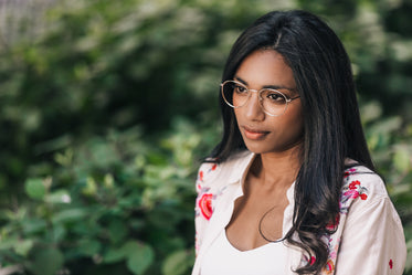 woman in glasses in front of greenery