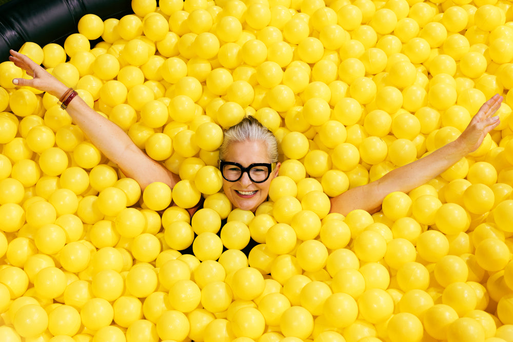 woman in glasses in yellow ball pool