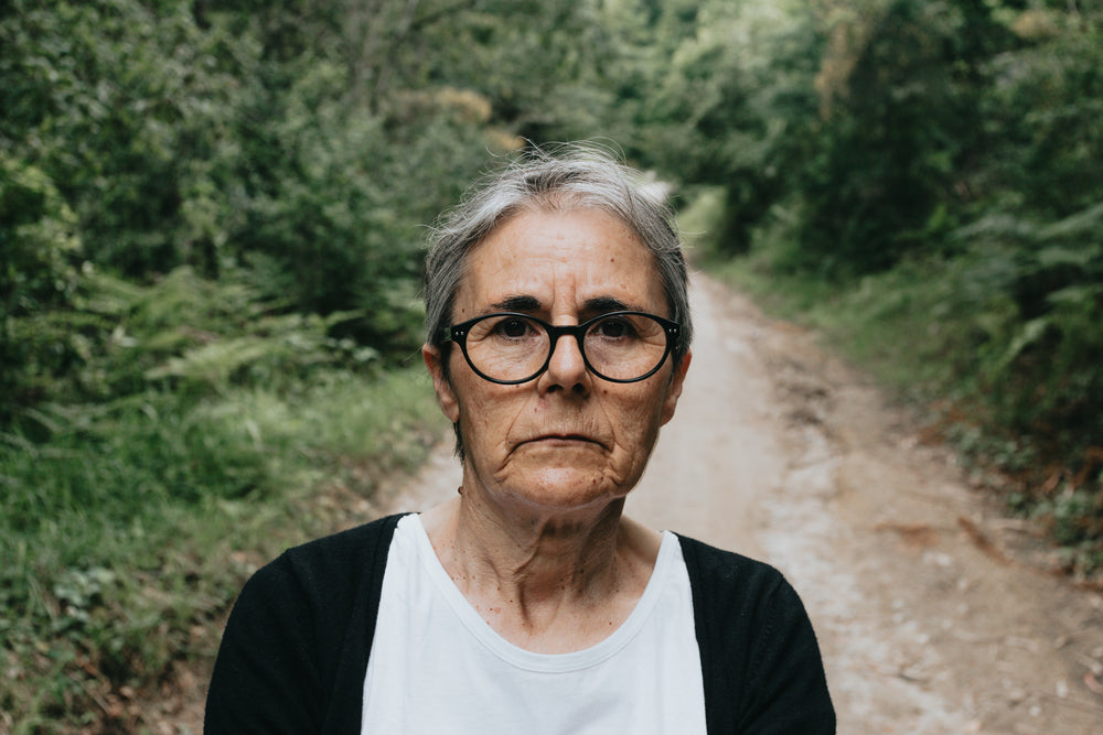 woman in glasses looks at the camera with a trail behind her