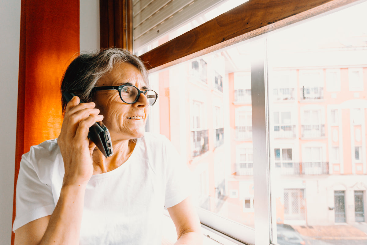 woman in glasses on the phone while looking out a window