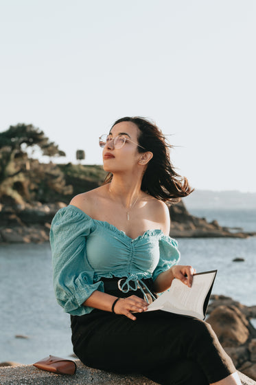 woman in glasses reads a novel by the water