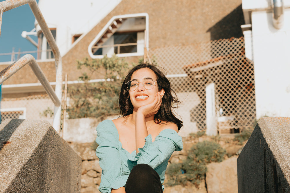 woman in glasses smiles in front of a camera