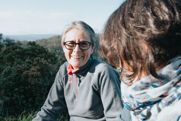 woman in glasses smiling at friend outdoors