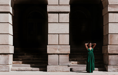 woman in green dress standing in front of archway
