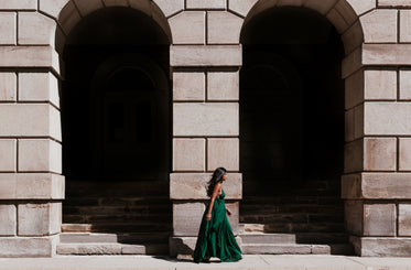 woman in green dress walking between archways