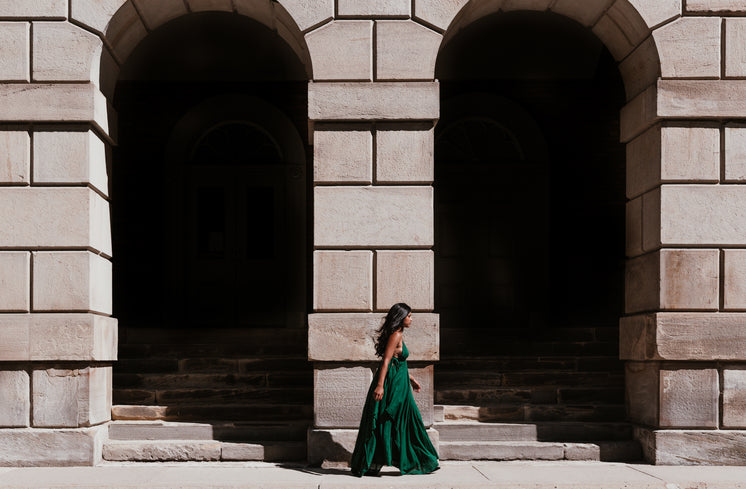 Woman In Green Dress Walking Between Archways