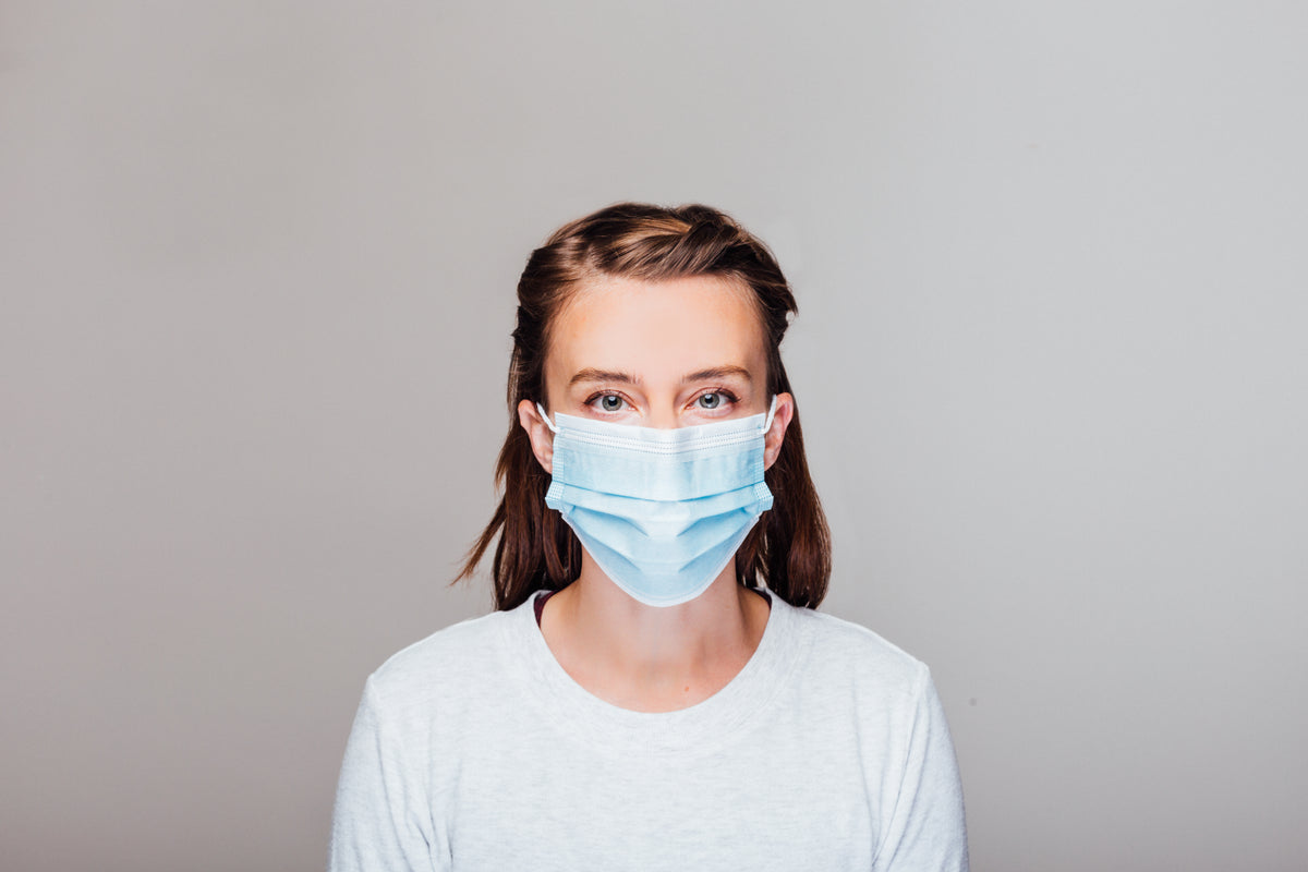 woman in grey sweater wearing disposable face mask
