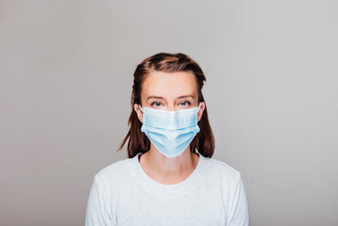 woman in grey sweater wearing disposable face mask