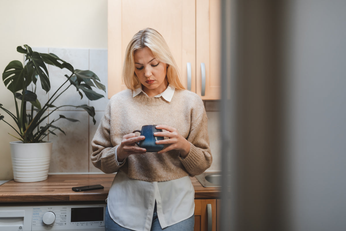 woman in her kitchen looks into her mug