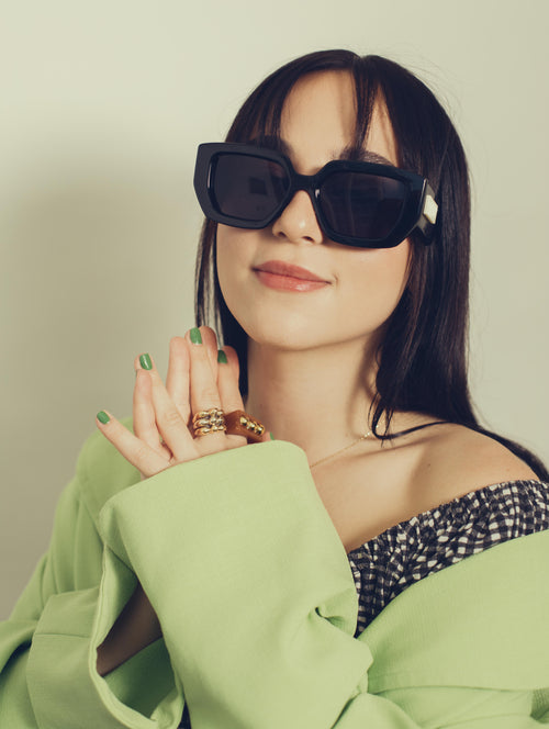 woman in large black sunglasses and a green shirt