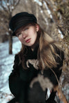 woman in newsboy cap in woods