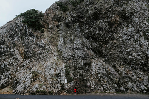 woman in red at foot of cliff