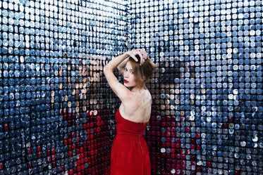 woman in red dress rests elbows against wall of mirrors