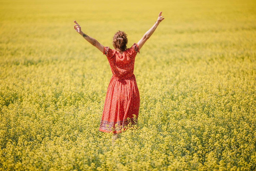 woman in red dress stands in field of yellow