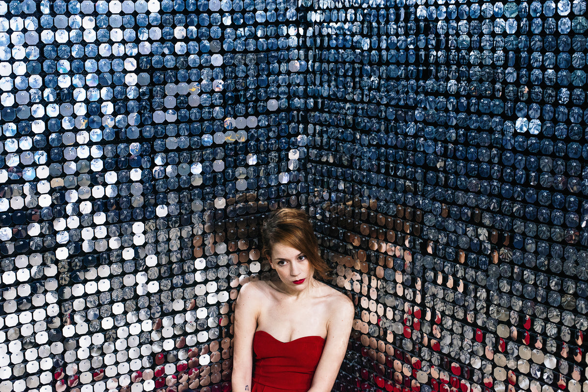 woman in red sits in corner against walls of mirrors