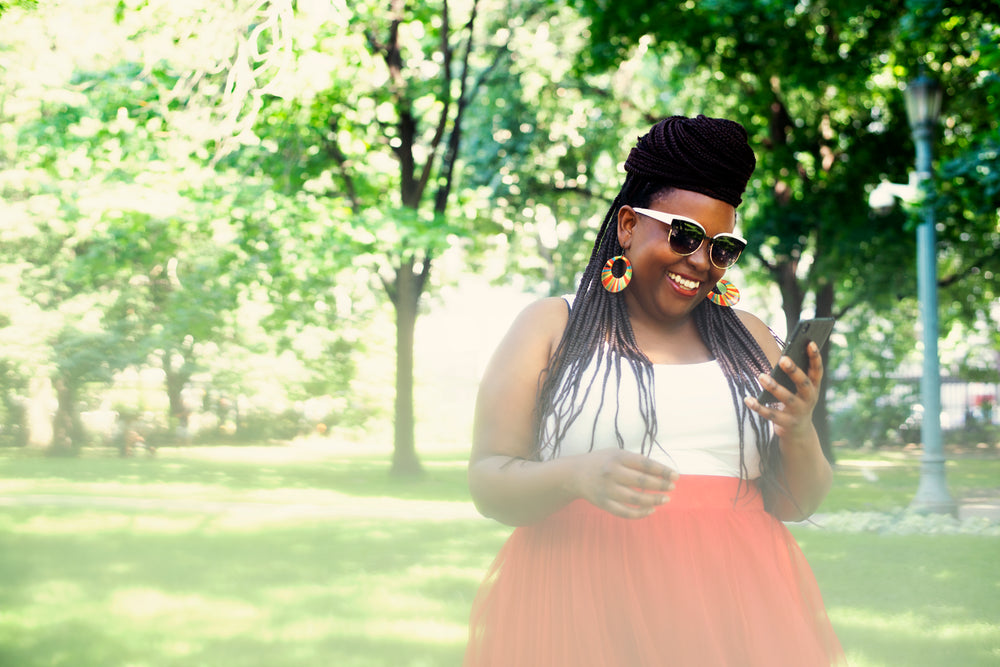 woman in red skirt and braids on phone