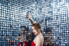 woman in red strokes a wall of sequin mirrors