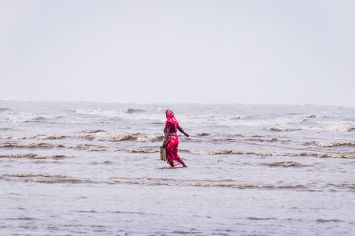 woman in red walking through shallow water