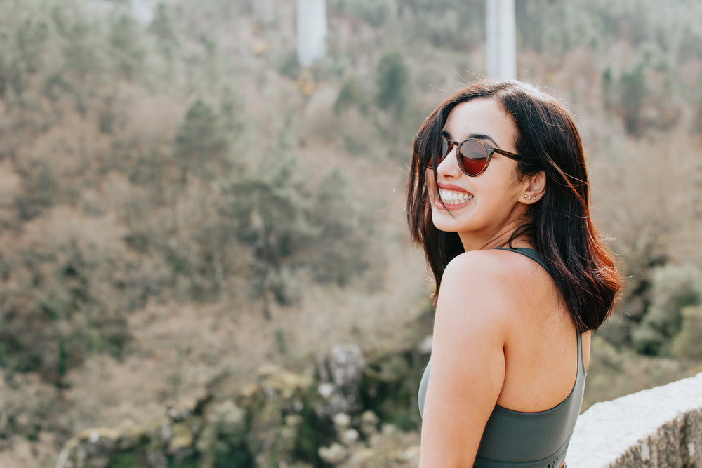 woman in round sunglasses smiles wide