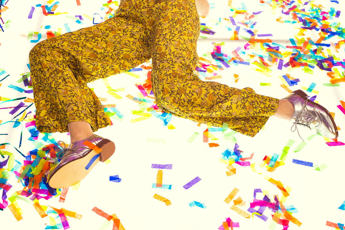 woman in silver leather oxfords laying in confetti