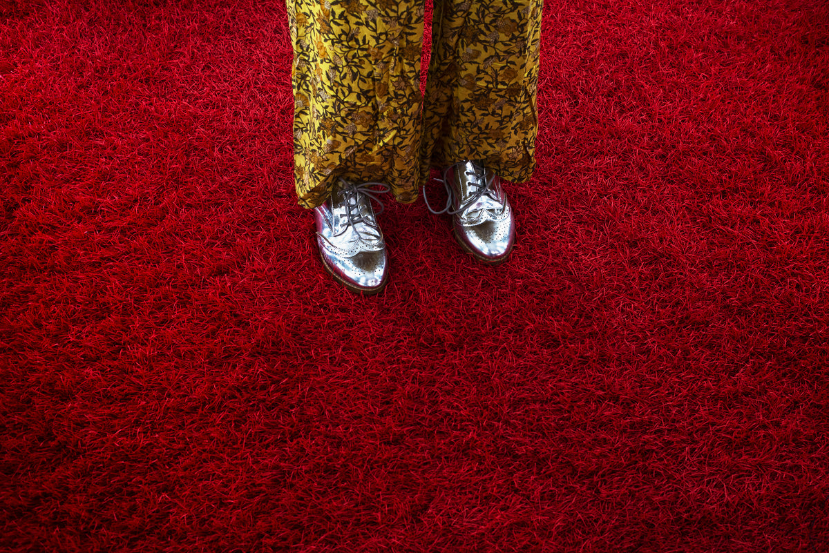 woman in silver oxfords crossing red shag carpet