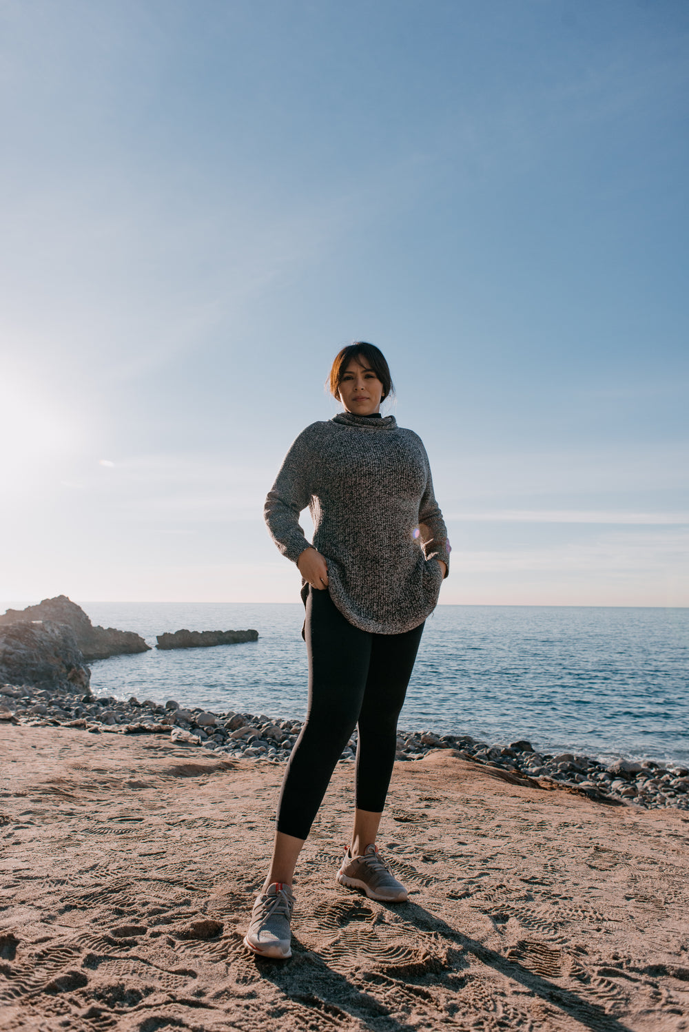 woman in sports clothes stands on a beach in the morning light