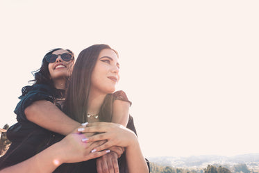 woman in sunglasses hugs the woman in front of her