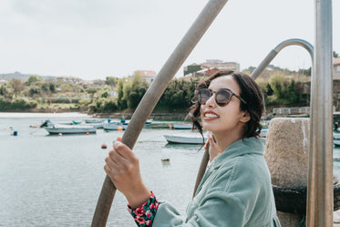 woman in sunglasses smile for the camera with boats below