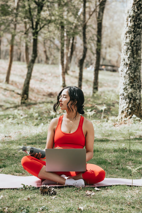 woman in vibrant red works on her laptop outdoors