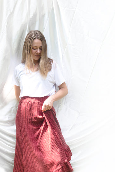 woman in white shirt and red skirt against cloth backdrop