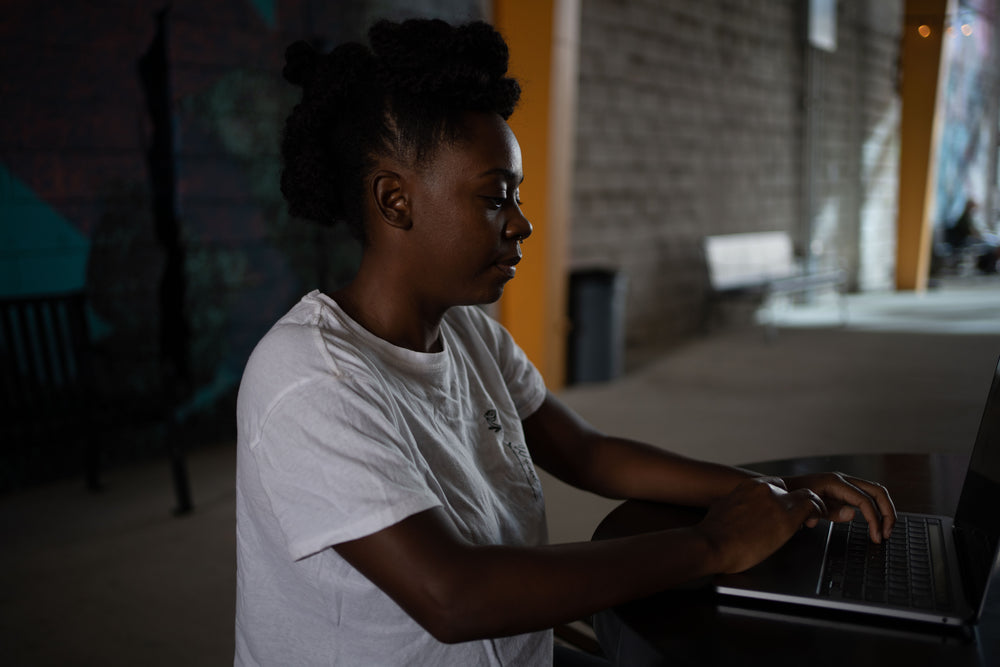 woman in white sits working away at her laptop