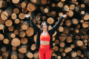 woman in workout clothing holds her hands above